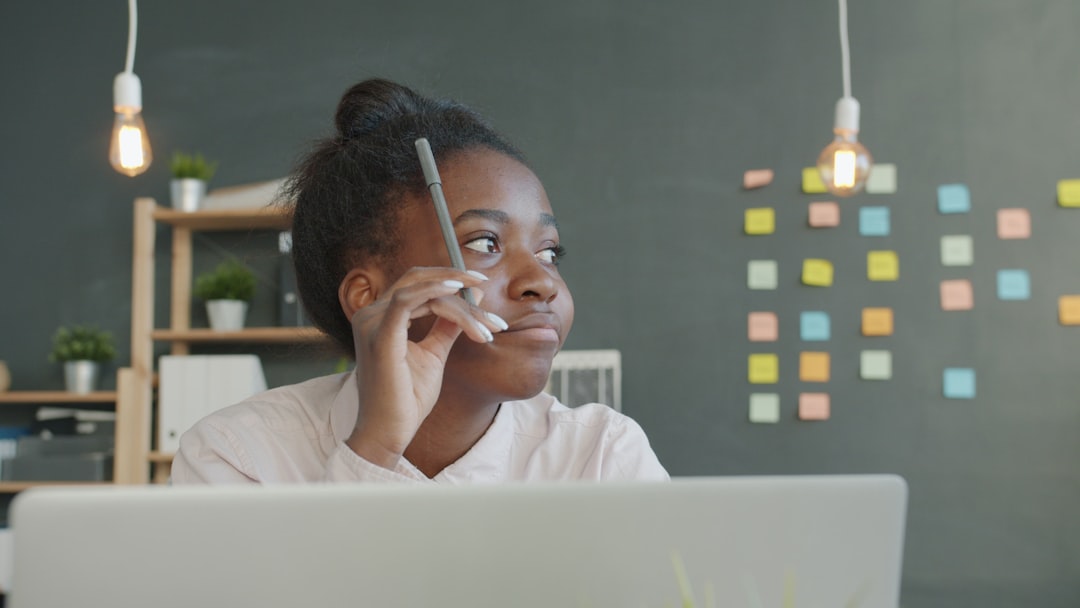 Young woman holding pencil, thinking at desk