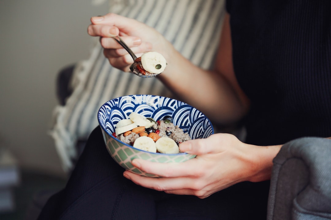 person holding spoon and bowl of food
