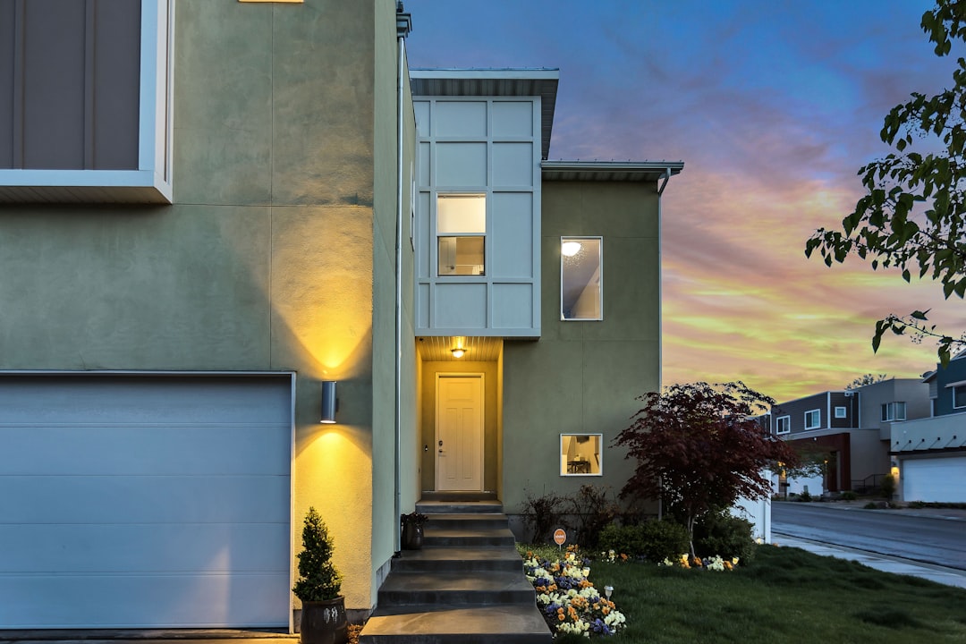 A modern house with a garage and lit doorway under a colorful evening sky