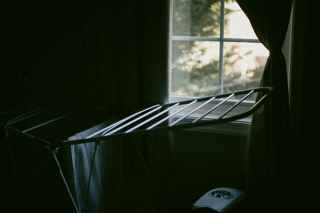 A bed in a dark room next to a window
