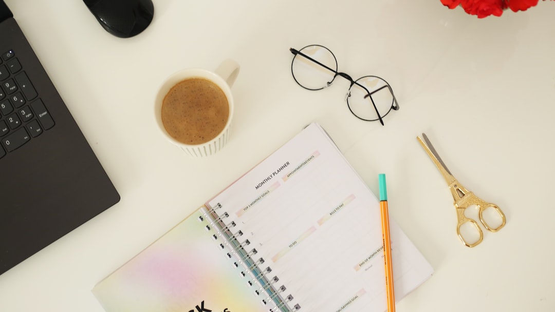pen, notebook, scissors, cup of coffee and eyeglasses