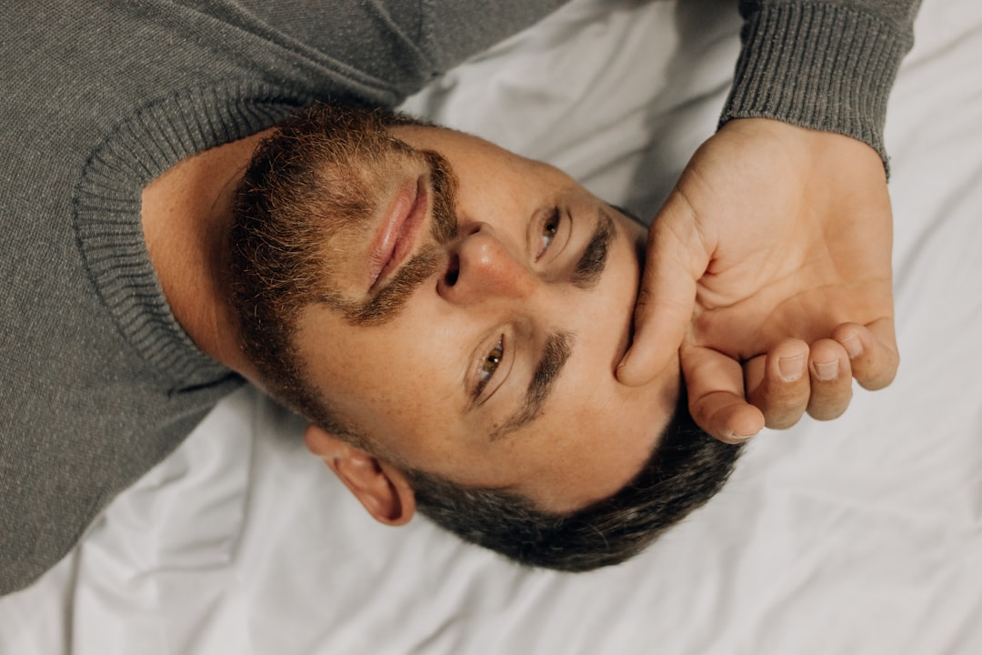 A man lies down with his hand on his head