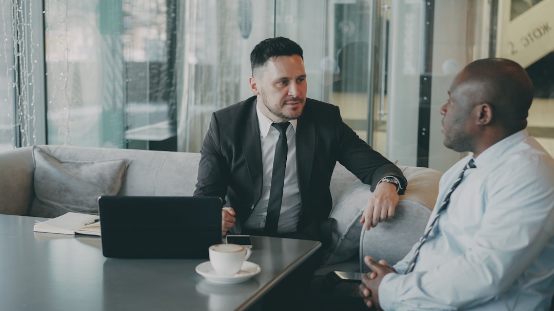 Two businessmen talking at a table with laptop