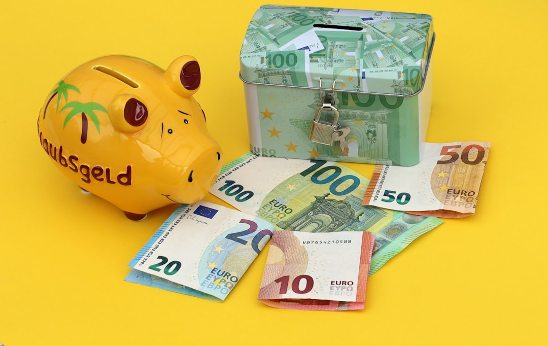 A yellow piggy bank and a locked metal box with euro banknotes on yellow