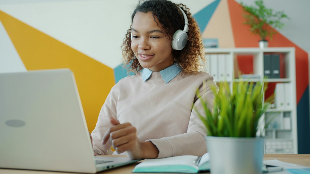 Young woman wearing headphones works on laptop