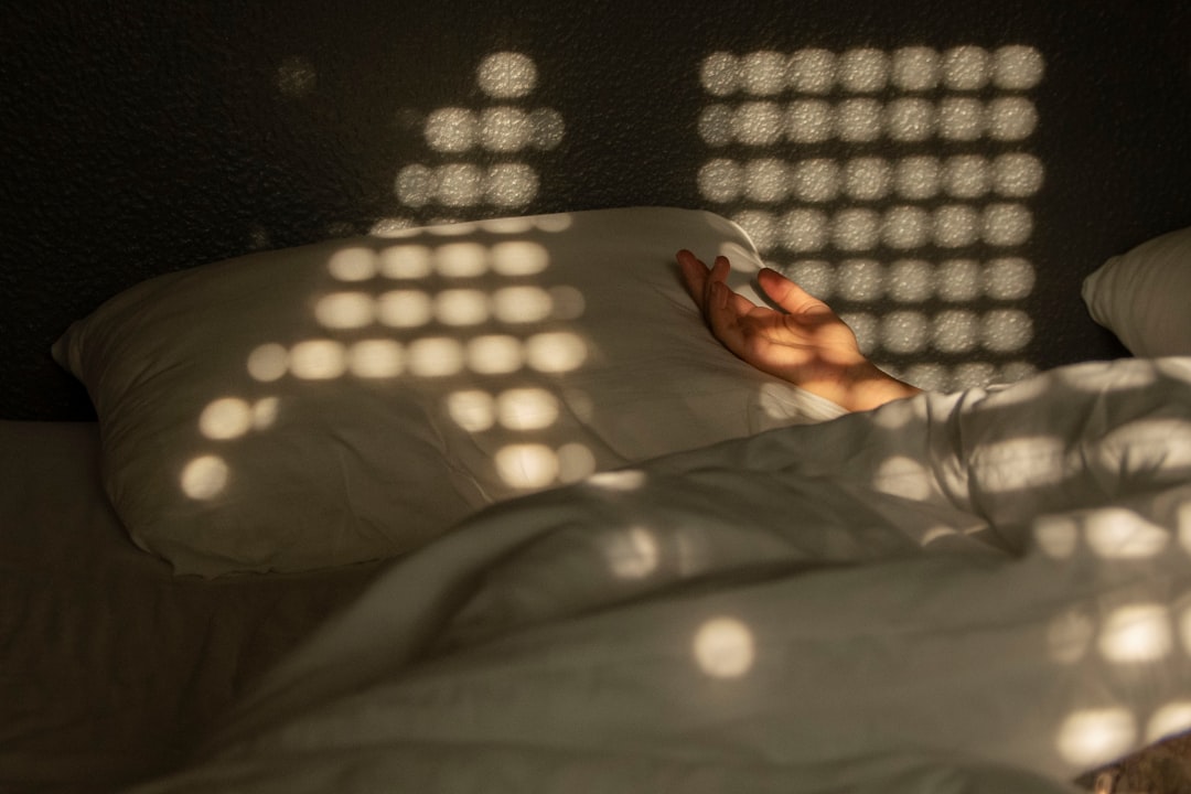 A person laying in a bed with a shadow on the wall