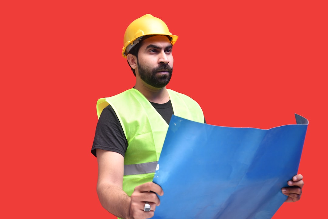 a man wearing a hard hat holding a blue and yellow flag